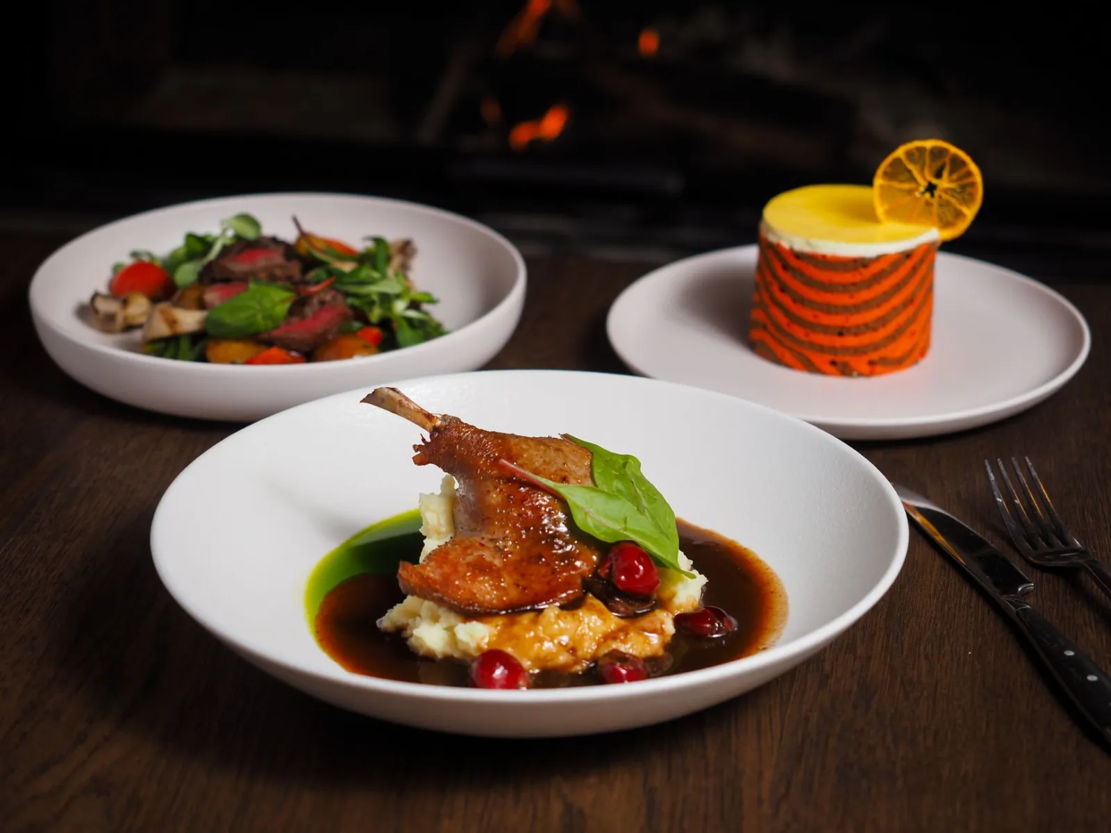 Elegant gourmet meal featuring roast chicken, salad, and dessert in a cozy setting.
